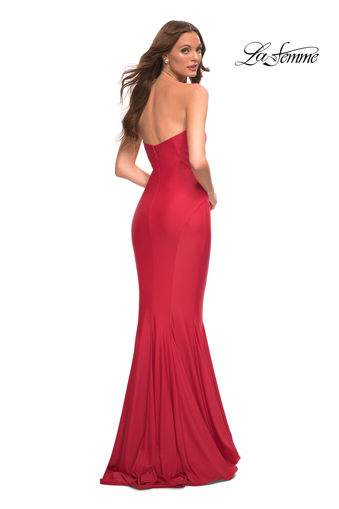 A woman stands looking over her shoulder in the La Femme Simple Mermaid Strapless Formal Dress, a fitted, floor-length red gown. The